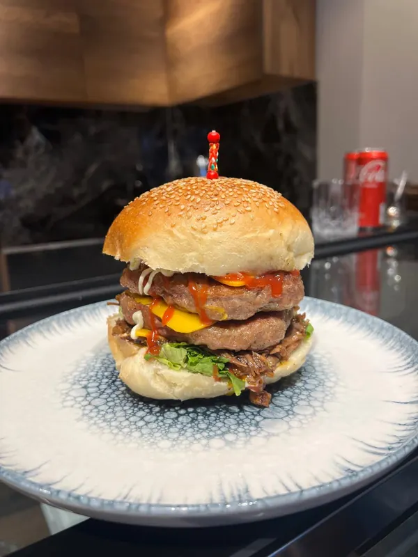 Halal double burger with melted cheese on a blue-rimmed plate