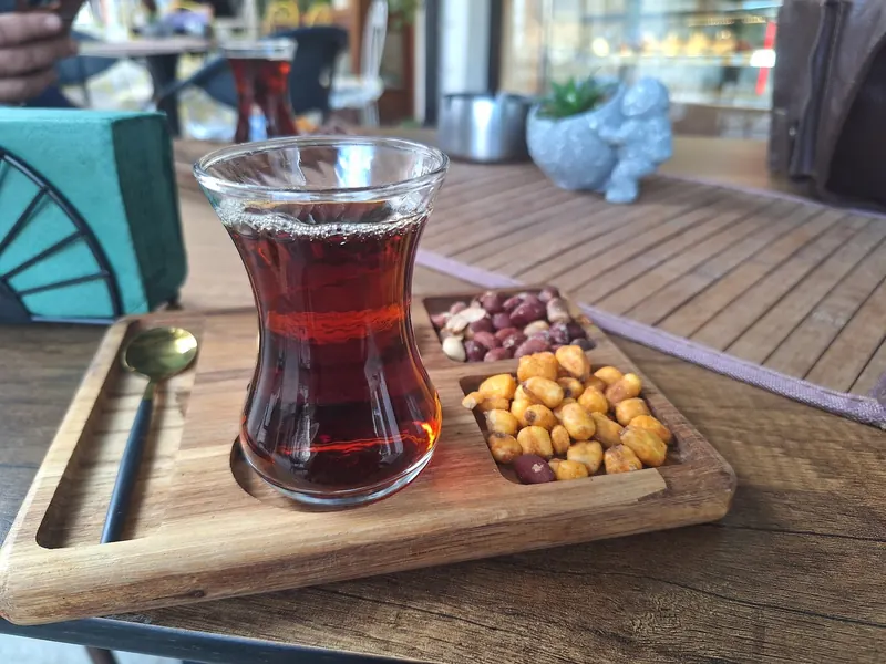Turkish tea in a tulip glass on a wooden tray with nuts